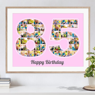 Schöne Geschenkidee zum Geburtstag personalisierte Zifferncollage 85 mit eigenen Bildern auf rosa Hintergrund in hellem Holzrahmen an eine Wand gelehnt neben einer Pflanze